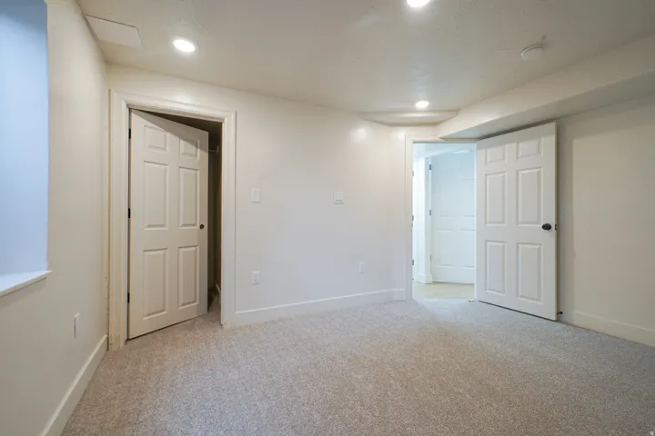 Recessed lighting, light-toned carpeting, white six-panel doors, and white trim