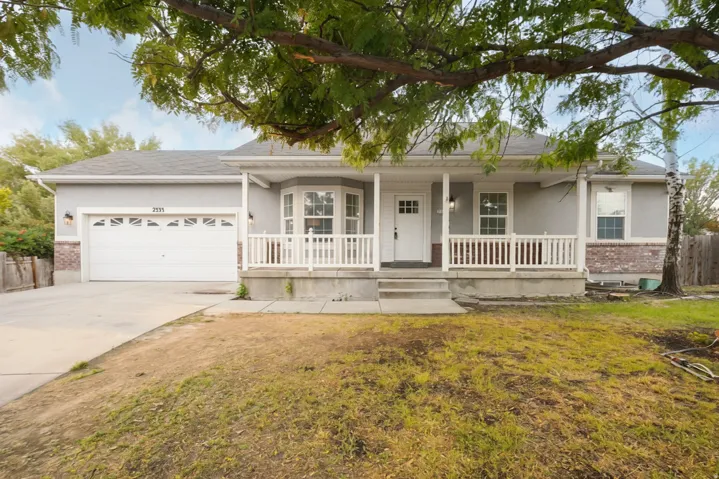 Light gray exterior with brick accents, covered front porch with white railing, and a bay window