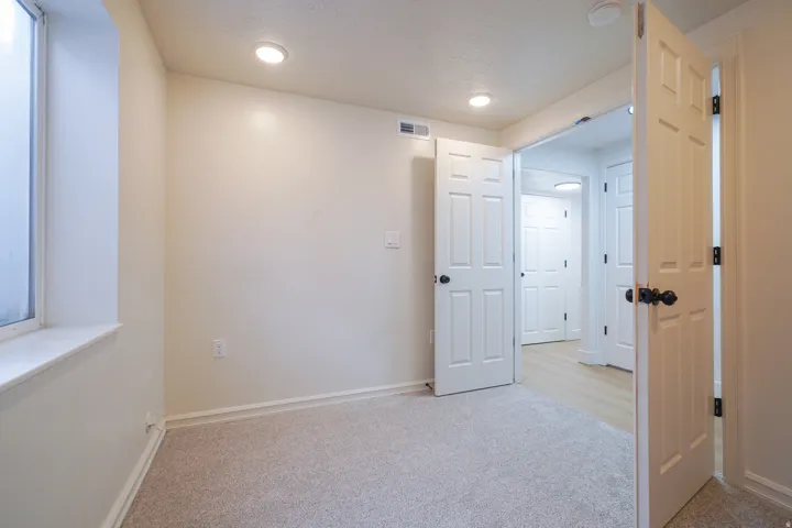 Recessed lighting, light-colored carpeting, white interior doors, and window with a deep sill