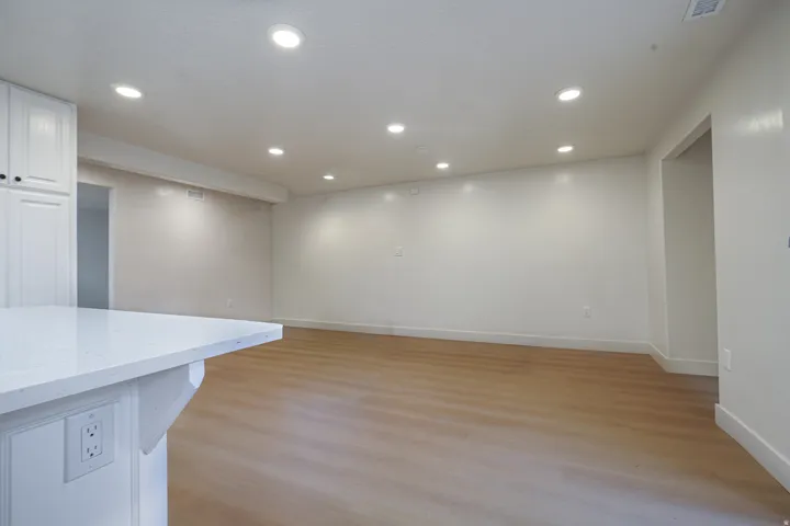 Recessed ceiling lighting, wood-finish flooring, white cabinetry, and a white countertop
