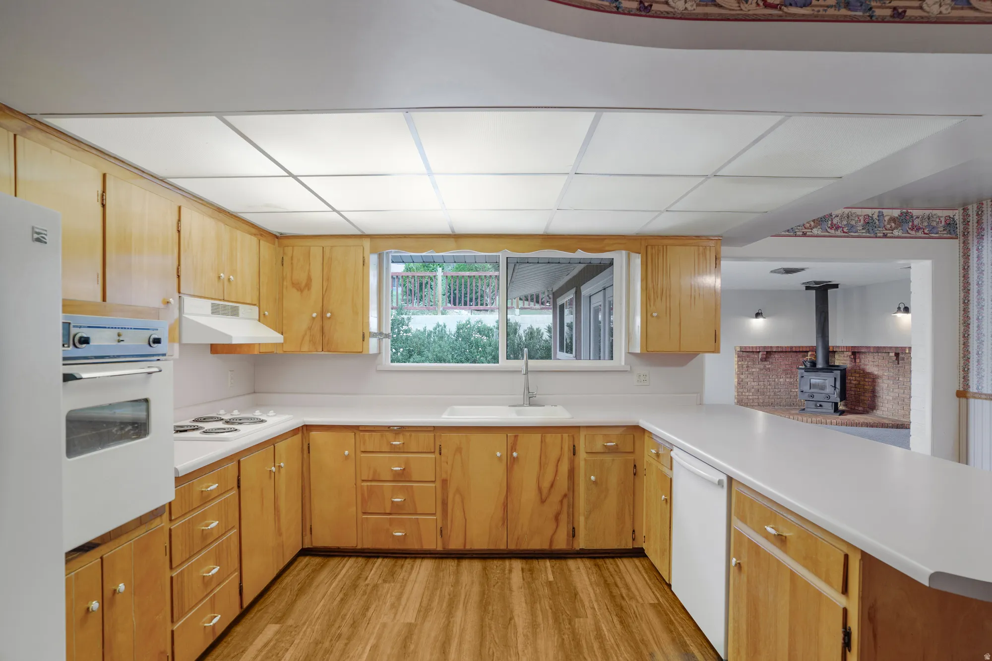 U-shaped kitchen featuring wood-finish cabinetry, white countertops, and wood-finish flooring