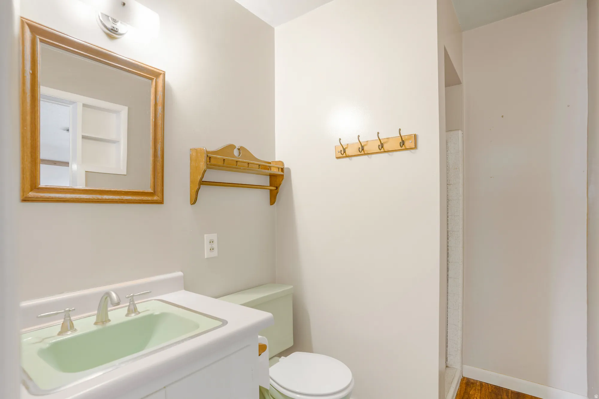Vanity with integrated sink, wall-mounted light fixture, and wood-framed mirror
