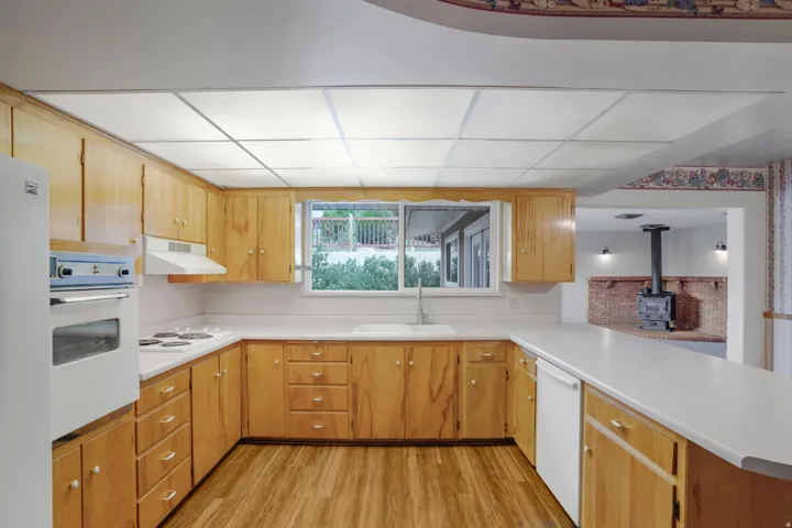 U-shaped kitchen featuring wood-finish cabinetry, white countertops, and wood-finish flooring