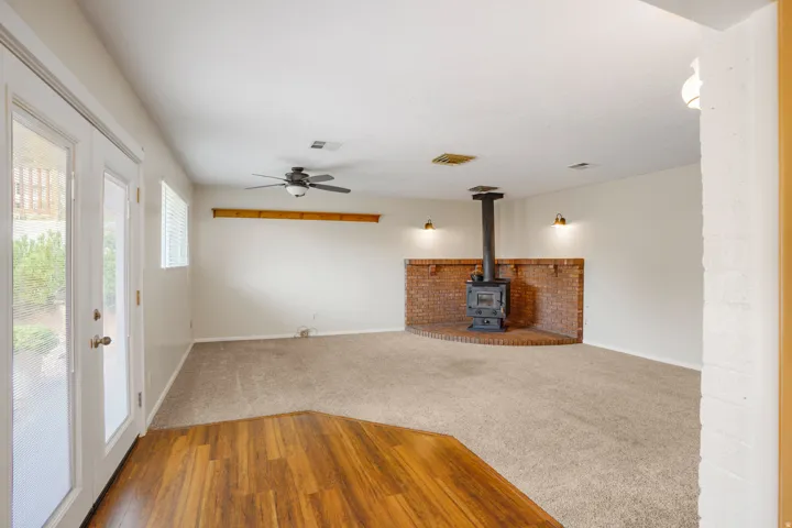 Wood-finish flooring at entry, leading to a carpeted living area with a ceiling fan