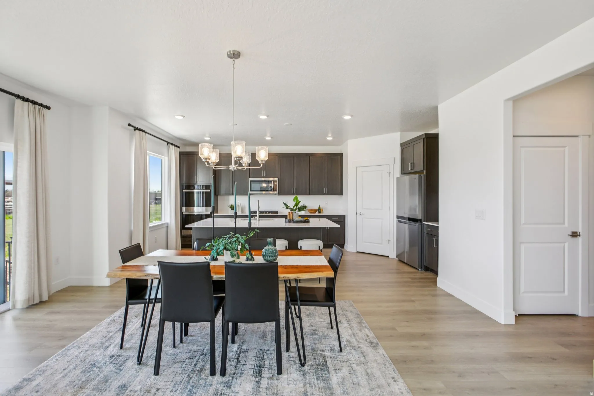 Open-concept dining area featuring wood-finish flooring, a contemporary chandelier, and a sliding glass door