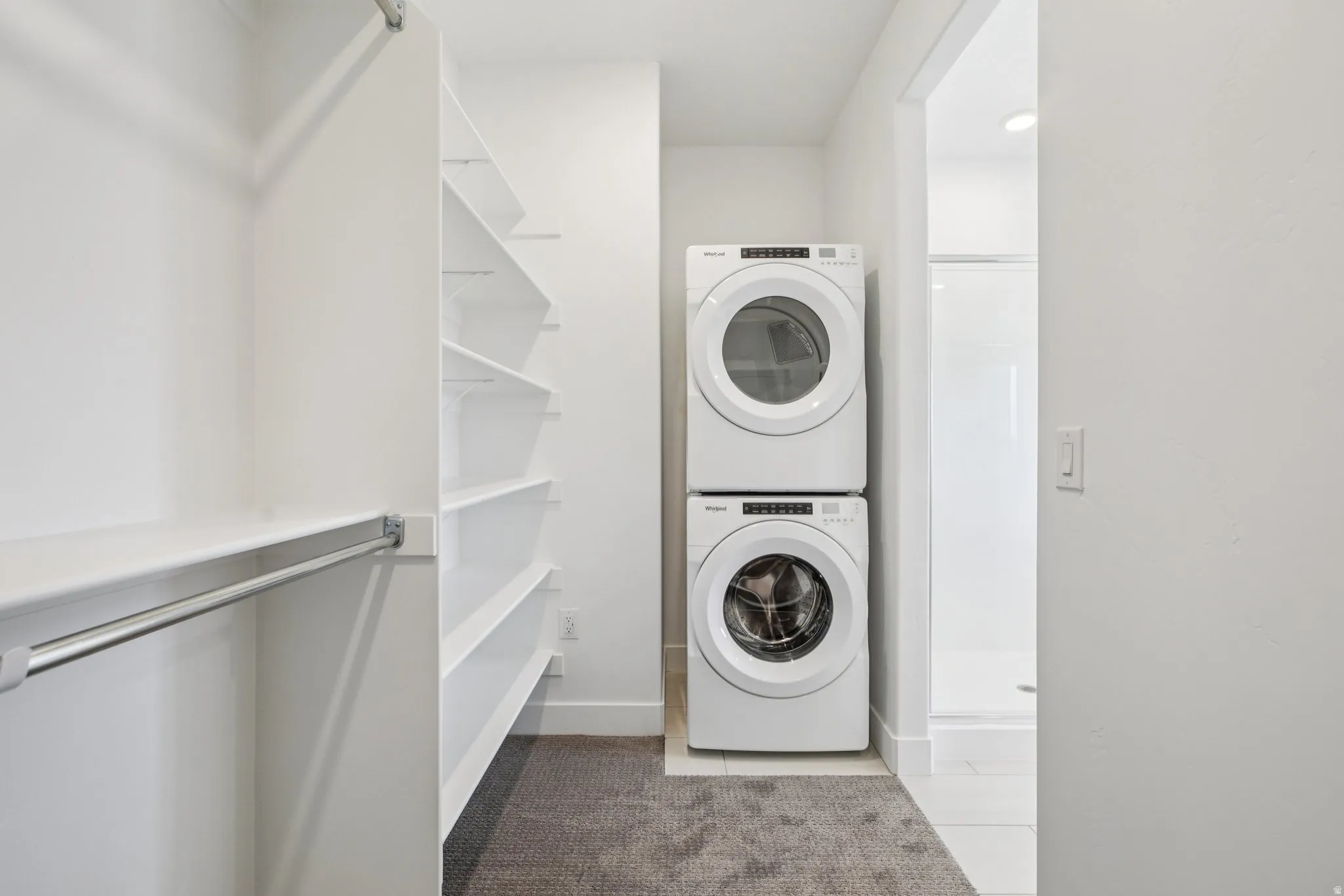 Integrated laundry appliances with white finish, built-in shelving, and closet hanging rod