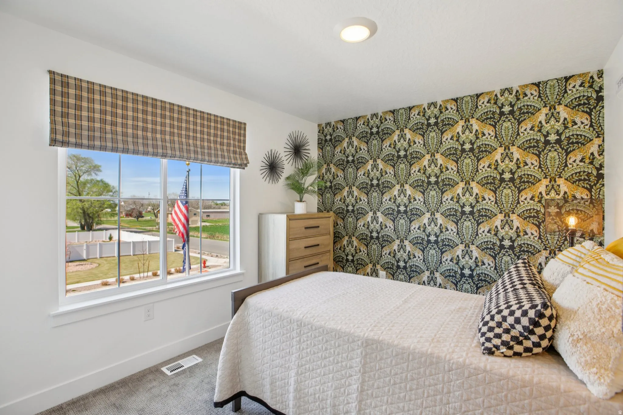 Recessed ceiling light, accent wall with patterned wallpaper, window with plaid window treatment, and carpeting