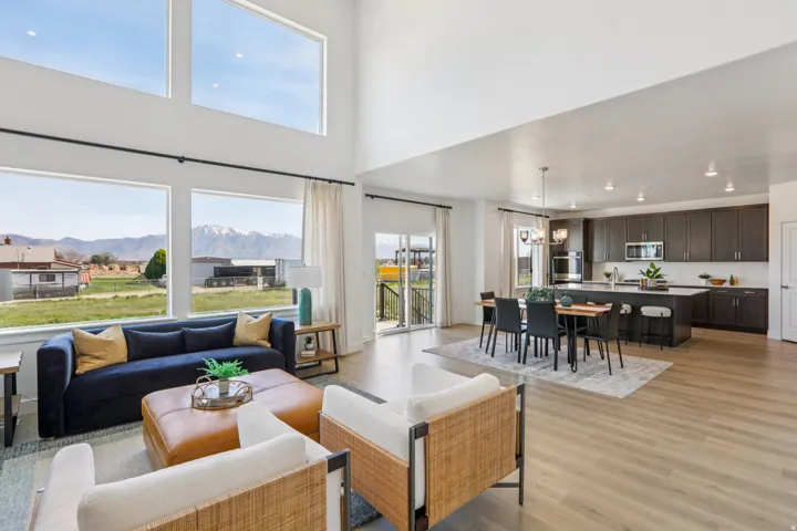 Soaring ceilings, expansive windows, wood-finish flooring, dark wood cabinetry, and a kitchen island with seating