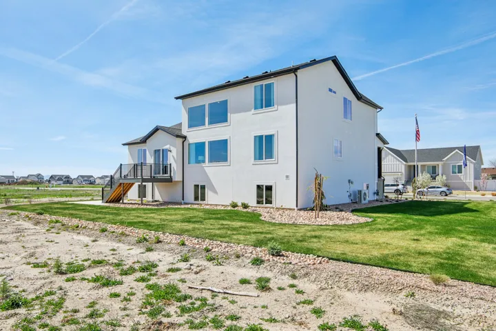 Two-story exterior with a deck, a concrete patio, and a landscaped lawn