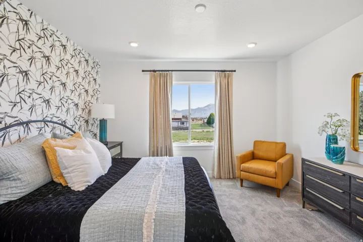 Recessed lighting, a feature wall with patterned wallpaper, soft carpeting, and a window with mountain scenery