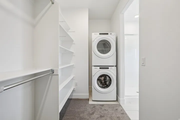 Integrated laundry appliances with white finish, built-in shelving, and closet hanging rod