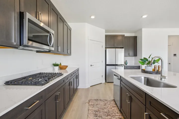 Kitchen featuring dark wood-finish cabinetry, stainless steel appliances, white countertops, and wood-finish flooring
