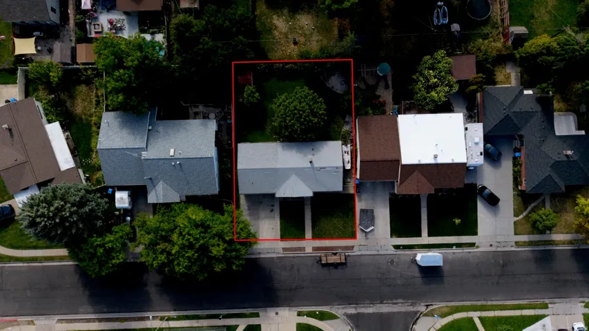 Gable roofline, concrete driveway, front yard with mature trees, backyard with expansive lawn, and concrete perimeter
