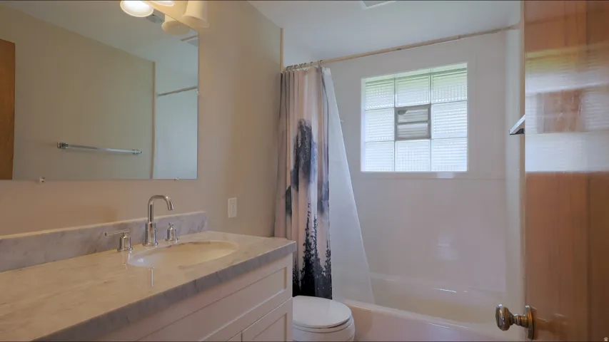 Vanity with undermount sink, dual-handle faucet, and stone countertop