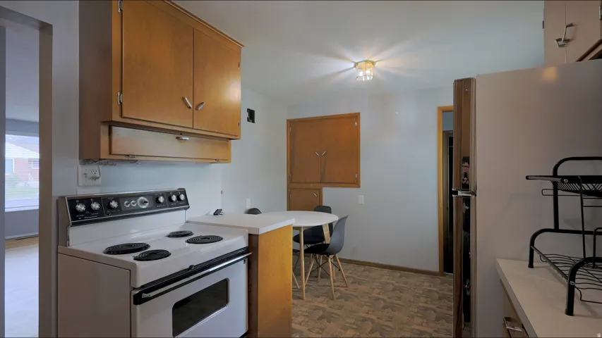 Wood-finish cabinetry, white kitchen range, and a ceiling-mounted light fixture