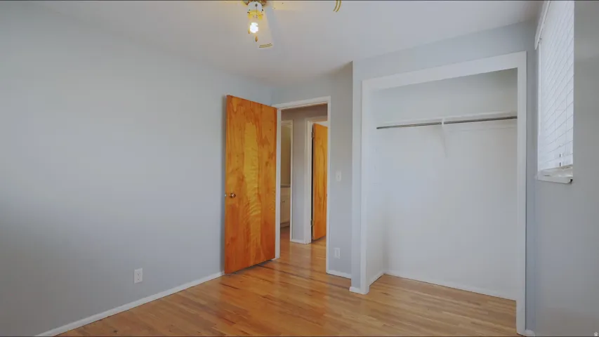 Hardwood flooring, light gray wall finish, natural wood-finish door, ceiling-mounted light fixture, built-in closet with hanging rod