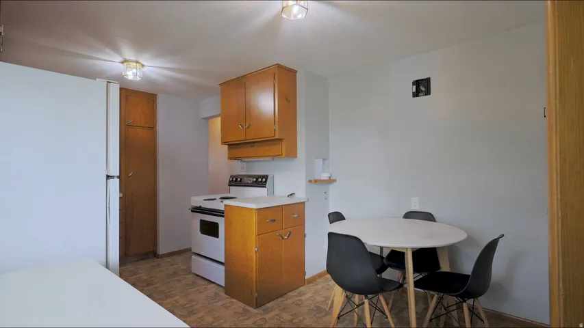 White appliances, wood-finish cabinetry, and overhead lighting