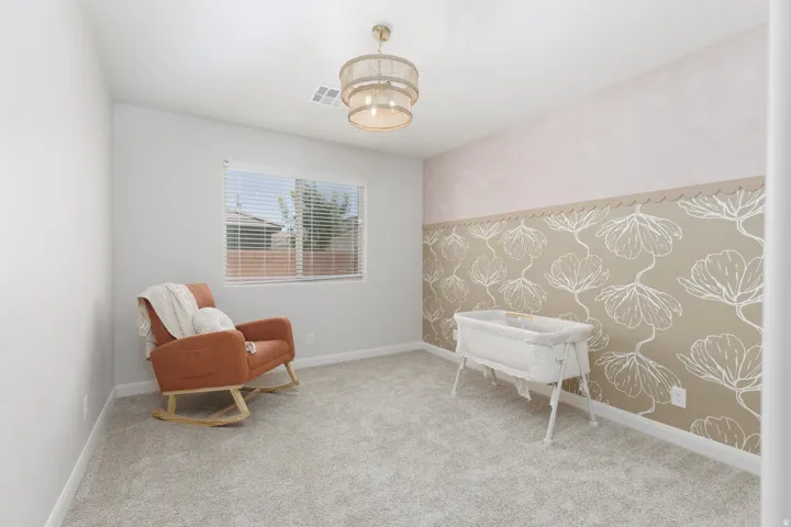 Carpeted room featuring a decorative accent wall with floral detailing, a window with horizontal blinds, and a drum-style ceiling light fixture