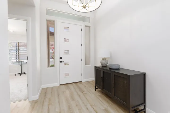 Entryway featuring wood-finish flooring, a modern chandelier, a transom window, and a sidelight