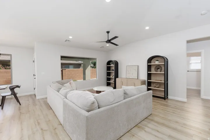 Expansive living area with wood-finish flooring, recessed lighting, and a contemporary ceiling fan