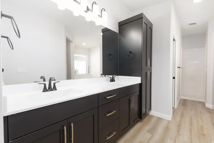 Dual basin vanity with white countertops, dark cabinetry, and matte black fixtures