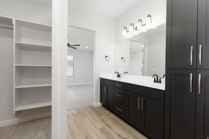 Dual vanity with dark wood-finish cabinetry, white countertops, and matte black fixtures