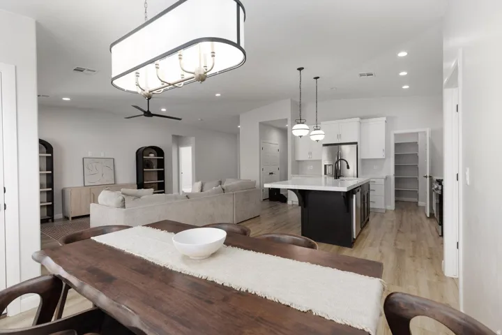 Open-concept living space featuring wood-finish flooring, a contemporary dining chandelier, and recessed lighting