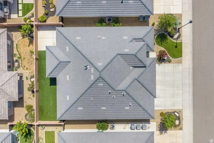 Pitched tile roof with multiple gables, rear artificial turf lawn, concrete driveway, and concrete walkways