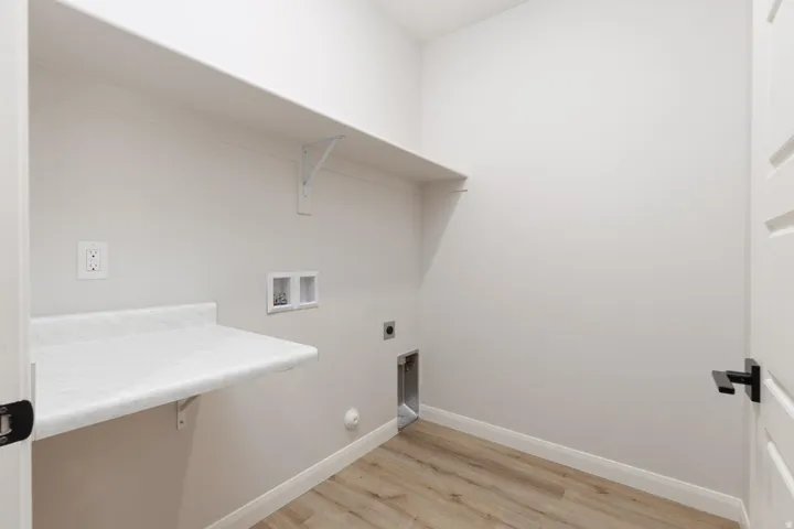 Utility room featuring wood-finish flooring, white walls, built-in shelving, and a built-in counter