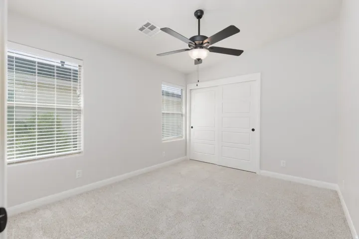 Recessed lighting, modern ceiling fan, two windows with blinds, sliding closet doors, and light-toned carpeting
