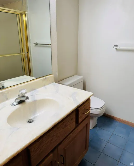 Vanity with an integrated sink, wood-finish cabinetry, and a gold-tone framed shower enclosure