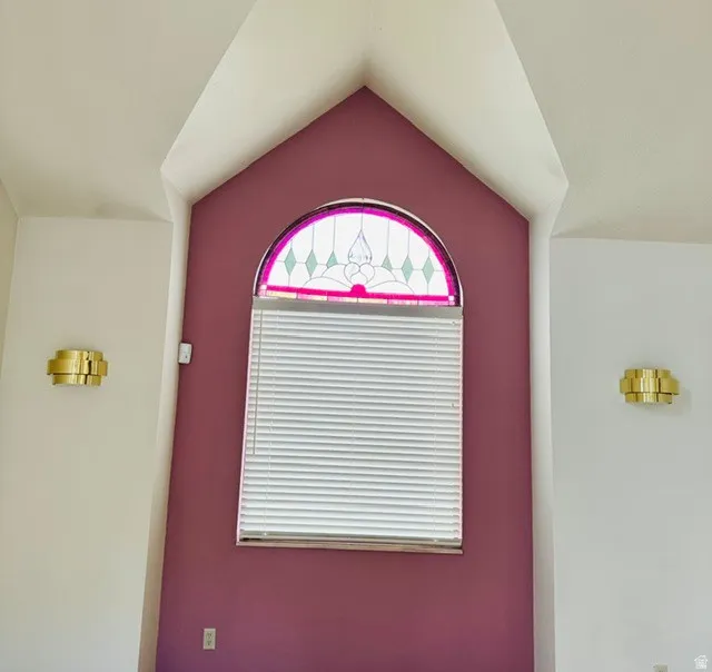 Arch window with decorative stained glass, flanked by two brass wall sconces