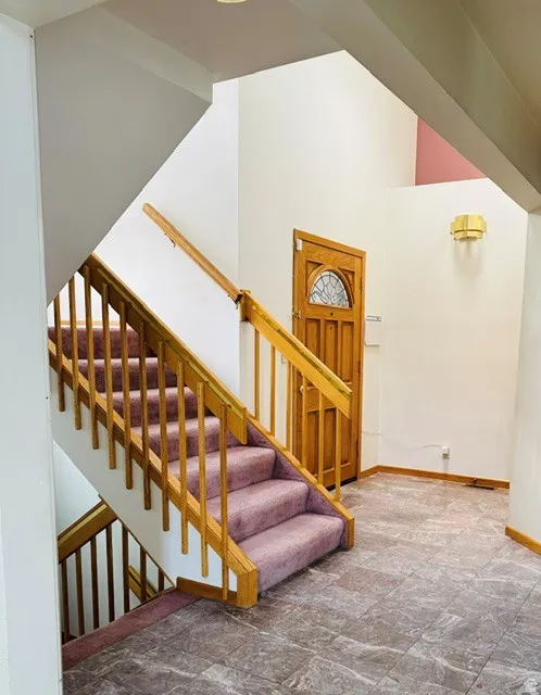 Foyer with tile flooring, a staircase featuring wood railings and carpeted treads, and a wood entry door with an arched glass panel