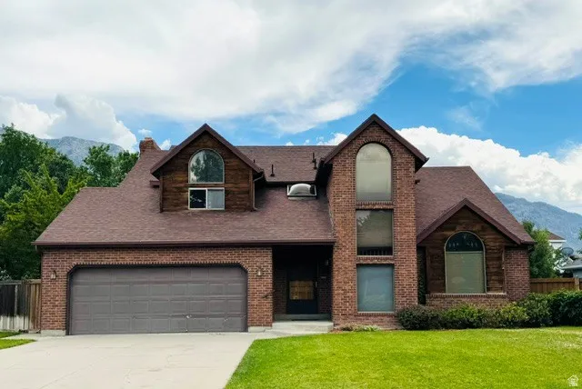 Brick exterior with wood accents, multiple arched windows, and an attached two-car garage