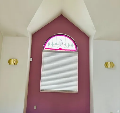 Arch window with decorative stained glass, flanked by two brass wall sconces