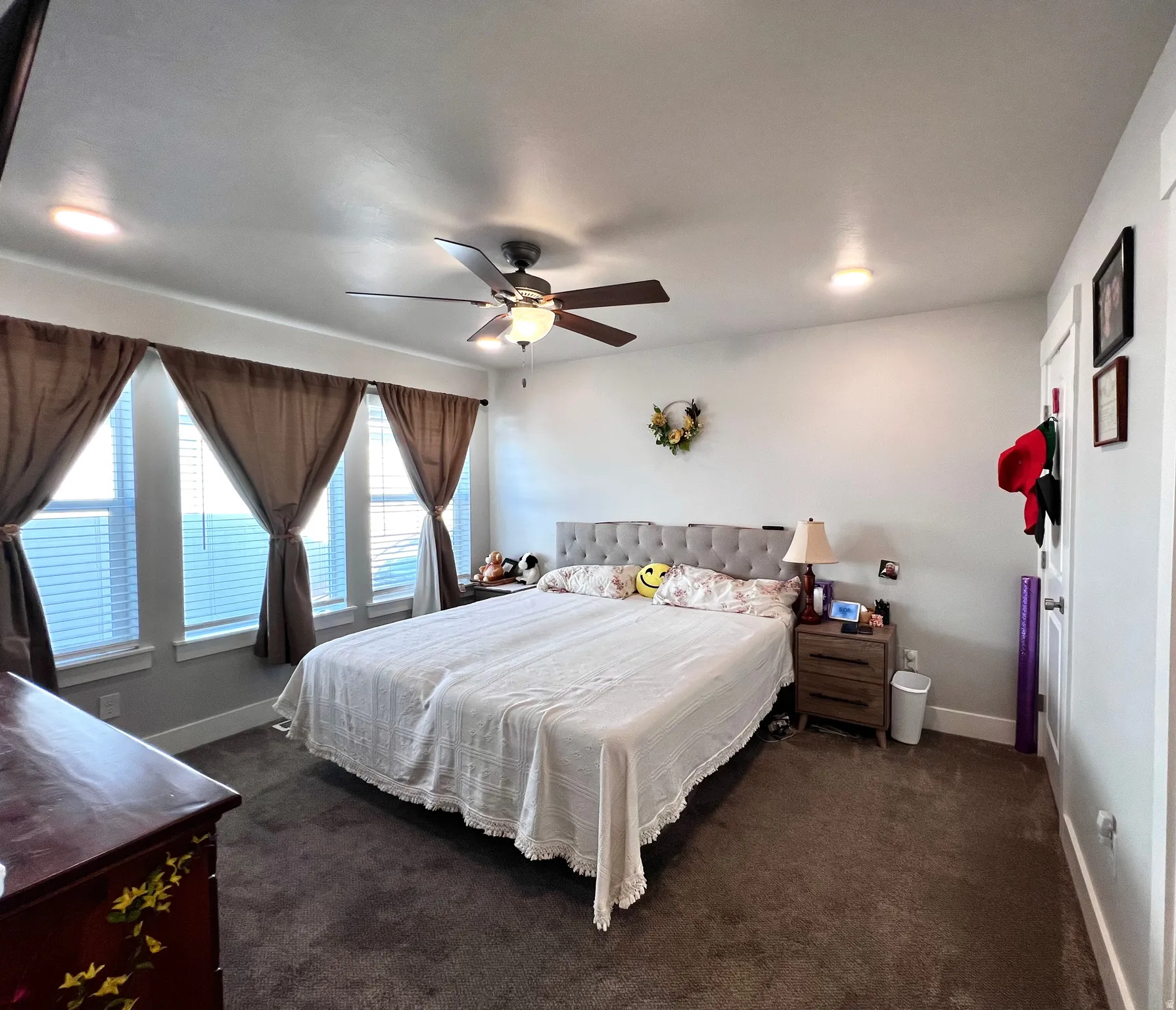 Primary bedroom. Recessed lighting, ceiling fan with integrated light, multiple windows with blinds, and neutral wall tones