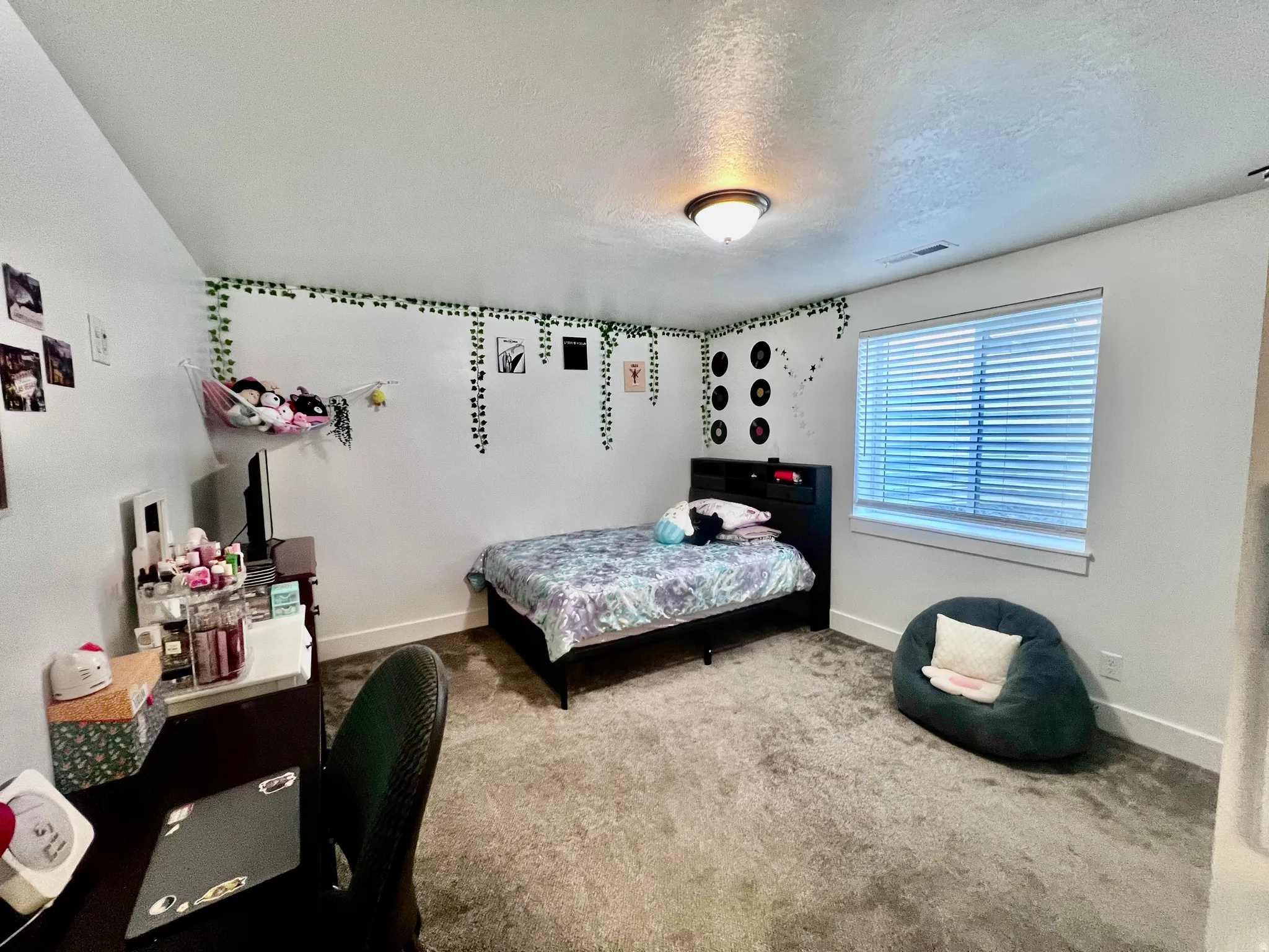 Basement apartment bedroom. White walls with contrasting trim, a window with horizontal blinds, a built-in ceiling light fixture, and carpeted flooring