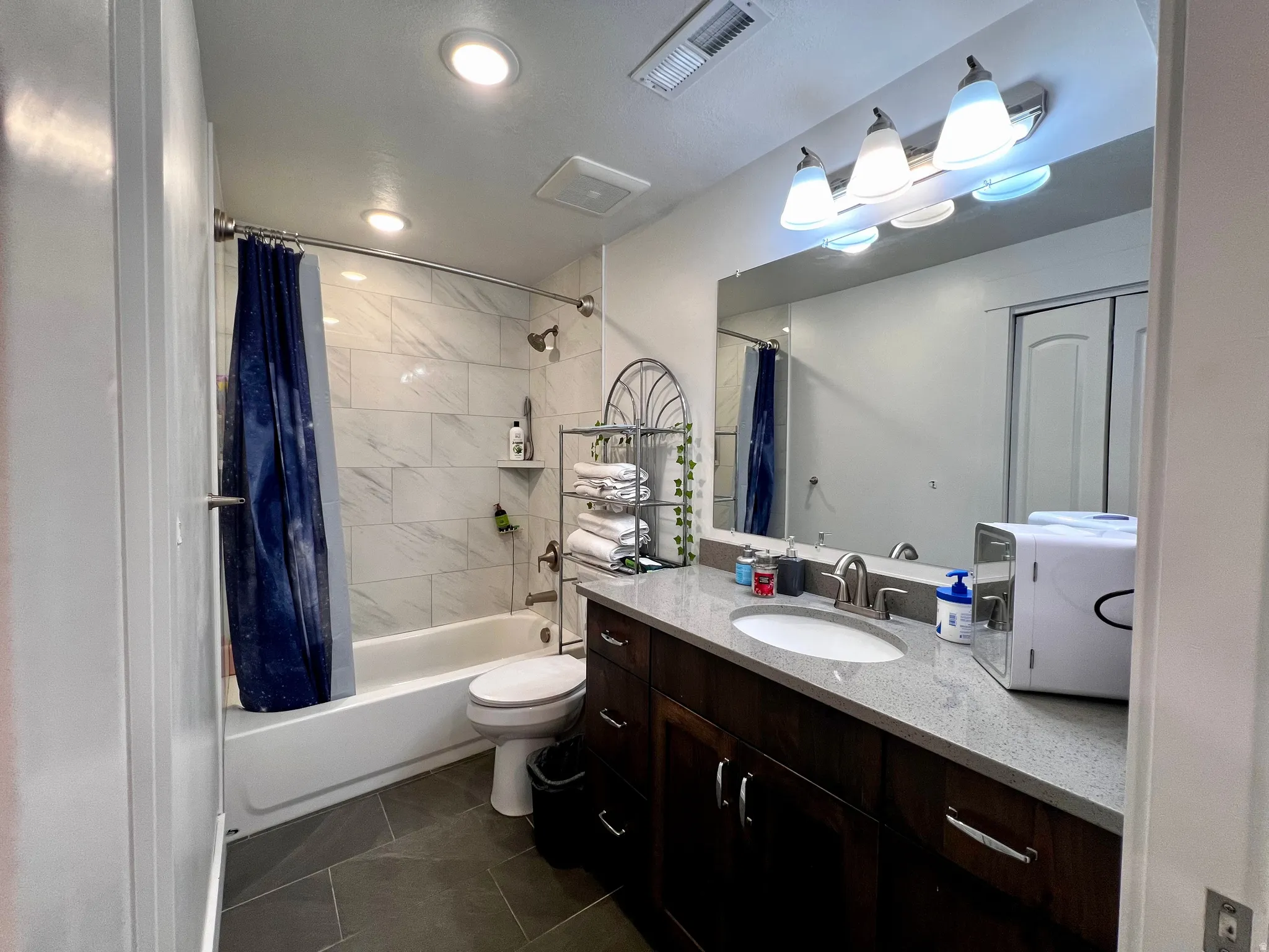 Basement apartment bathroom featuring a dark wood-finish vanity with a light-colored countertop, an undermount sink, and a large mirror