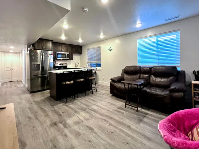Basement apartment kitchenette with dark wood-finish cabinetry, stainless steel appliances, and an island with counter seating