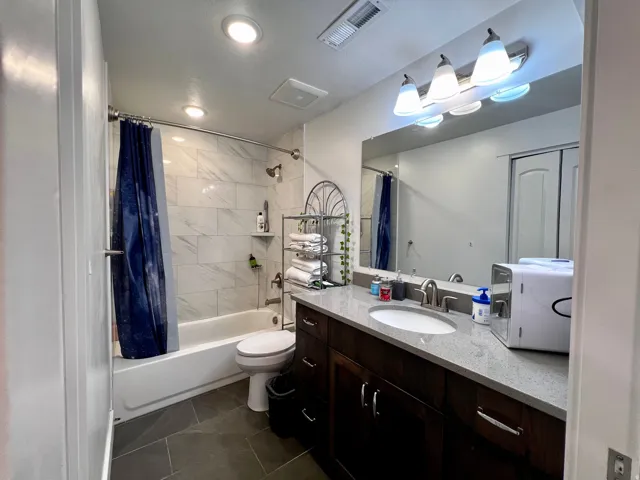 Basement apartment bathroom featuring a dark wood-finish vanity with a light-colored countertop, an undermount sink, and a large mirror
