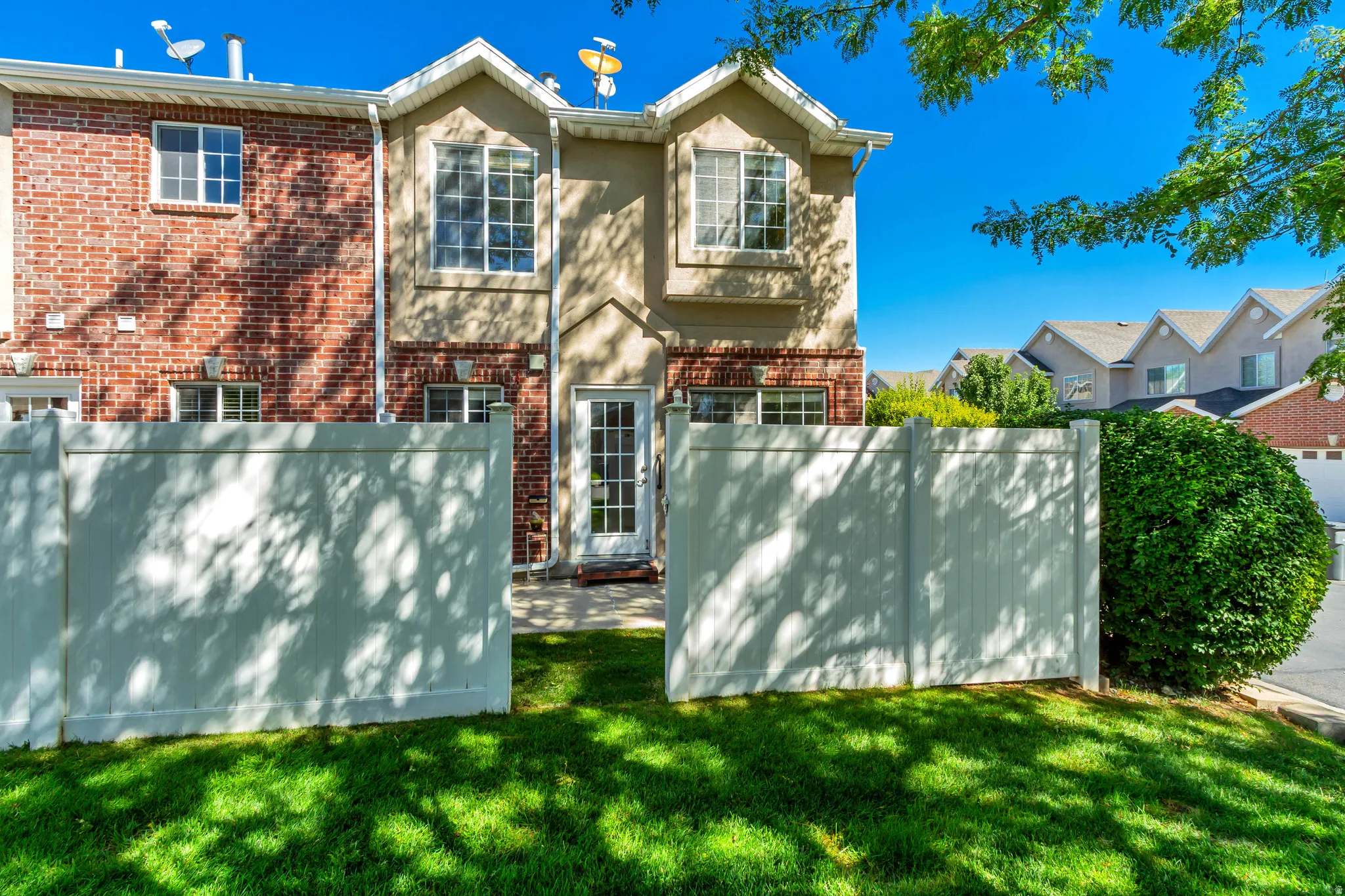 Fenced backyard with a grassy lawn, brick and stucco exterior, and a glass-paneled rear entry door
