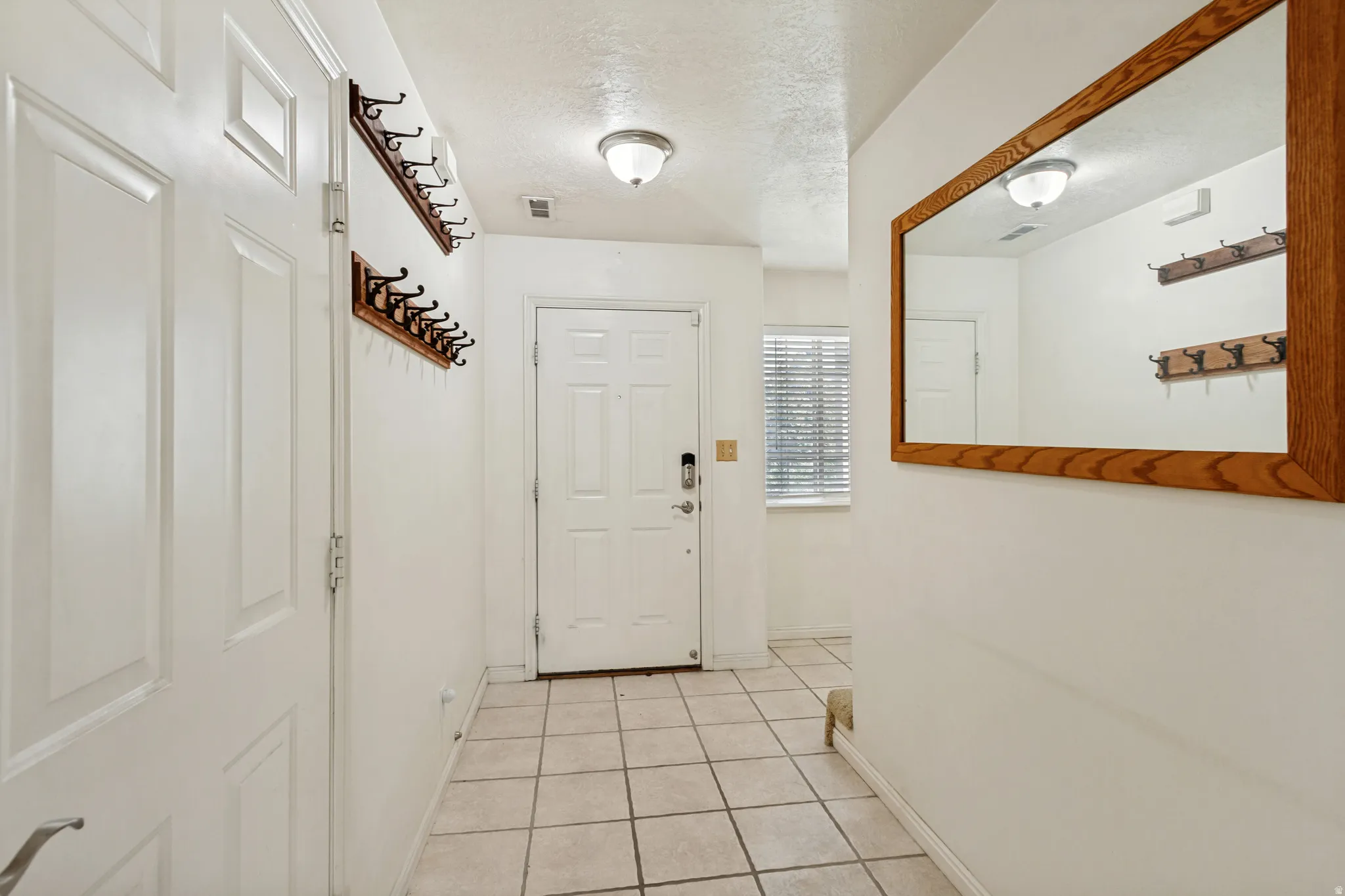 Entryway featuring tile flooring, white paneled doors, and a wood-framed mirror