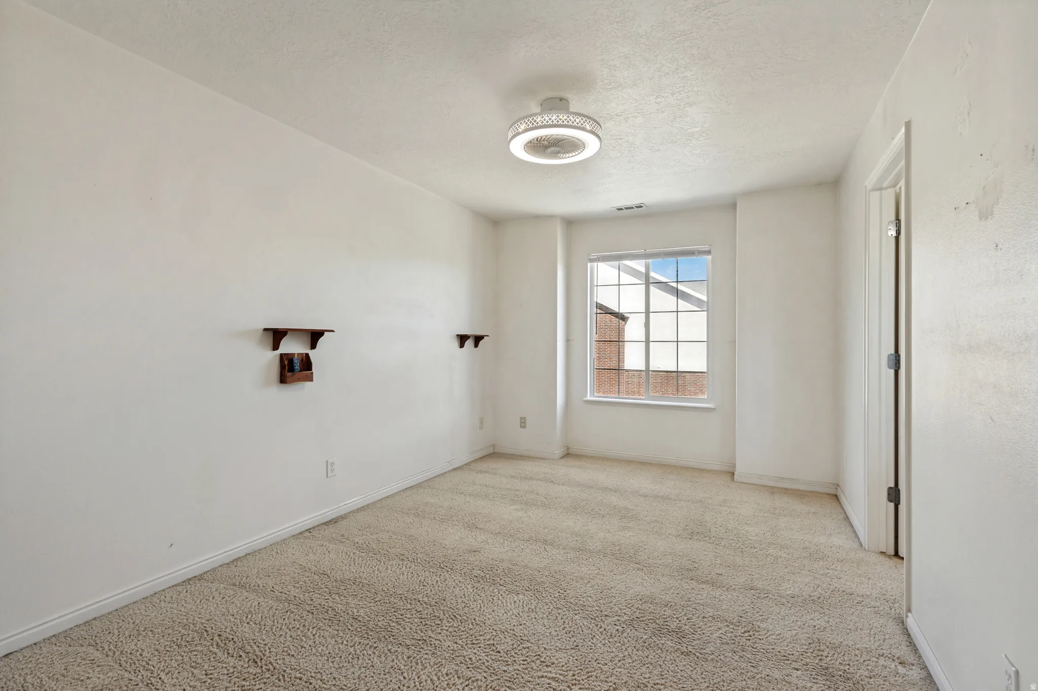 Recessed window with grid pattern, carpeted flooring, and a ceiling-mounted light fixture with a fan