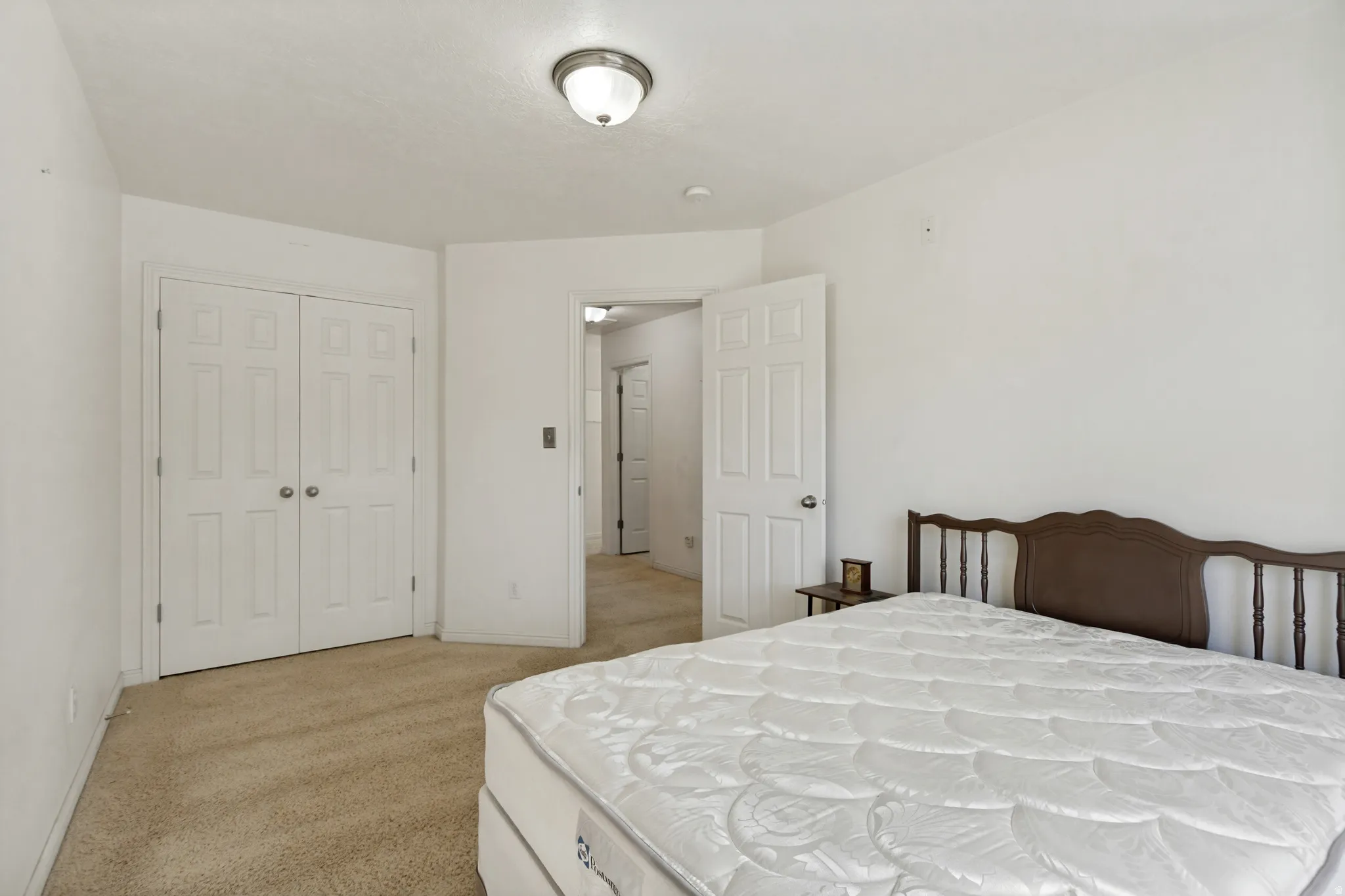 Plush carpet flooring, six-panel bi-fold closet doors, and an overhead flush-mount light fixture