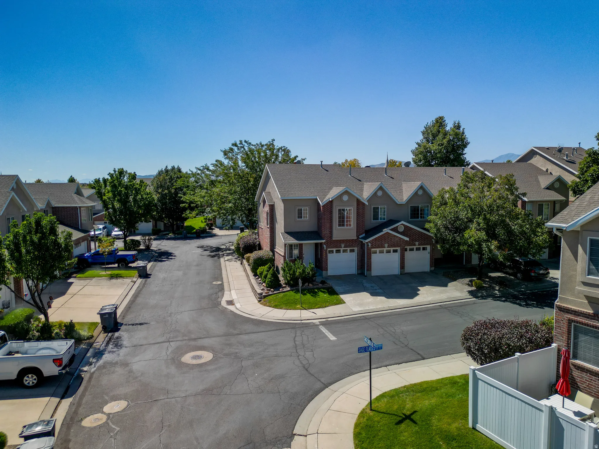 Townhome exterior with a brick and siding facade, multiple garage doors, and mature landscaping
