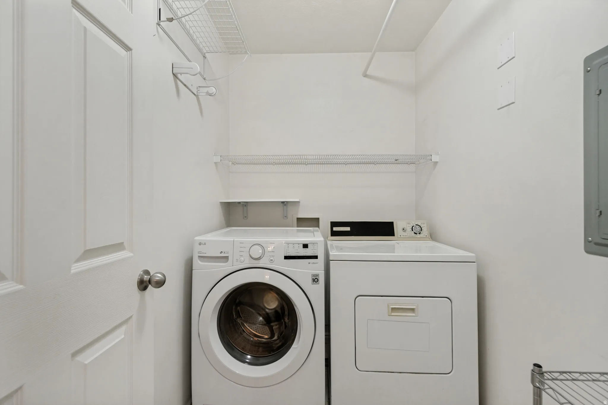 Dedicated laundry area featuring a full-size washer and dryer, wire shelving, and a built-in clothes rod