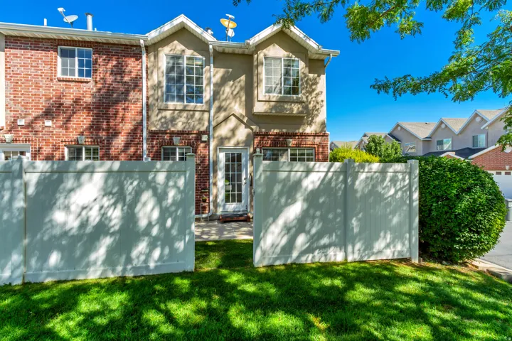 Fenced backyard with a grassy lawn, brick and stucco exterior, and a glass-paneled rear entry door