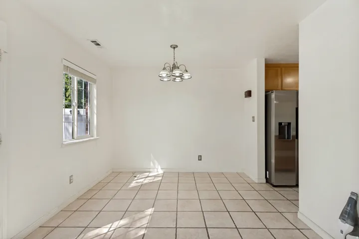 Open-concept room featuring tile flooring, a multi-light chandelier, and a large window