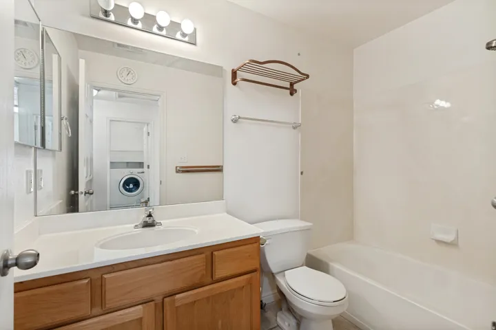 Wood-finish vanity with an integrated sink and chrome faucet, large vanity mirror, and a four-bulb vanity light fixture