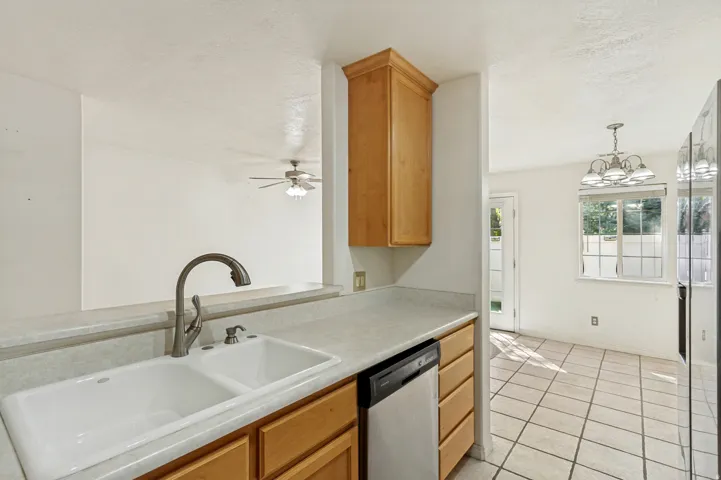 Kitchen featuring a double basin sink, stainless steel dishwasher, wood cabinetry, and a ceiling-mounted light fixture